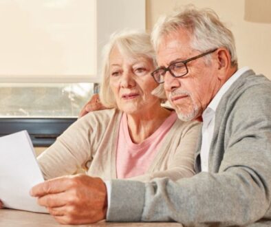 An older couple sits together at a table, seriously discussing options to switch Medicare plans.