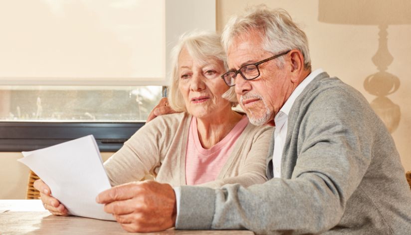 An older couple sits together at a table, seriously discussing options to switch Medicare plans.