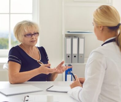 Older woman discusses GLP-1 Medicare coverage with a female doctor at a desk in a bright, organized office.