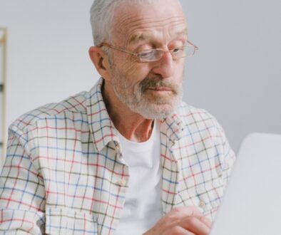 Older man reviewing Medicare plan information on a laptop before the Annual Enrollment Period.
