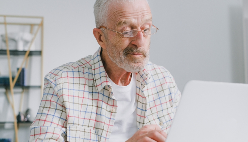 Older man reviewing Medicare plan information on a laptop before the Annual Enrollment Period.